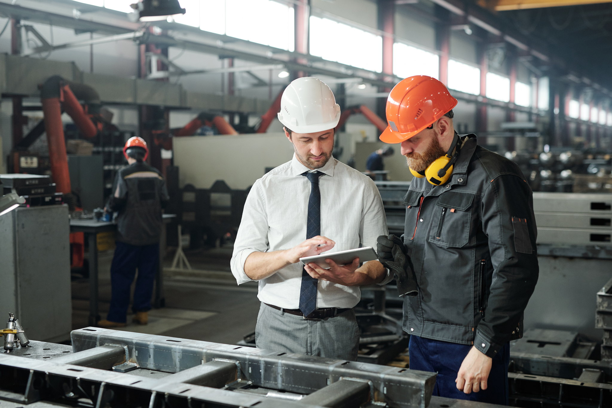 Operations manager and engineer reviewing workers' compensation data on a tablet in a factory