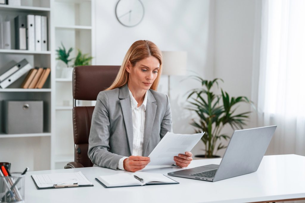 An advisor reviewing workers' compensation loss runs and premium documents at her desk